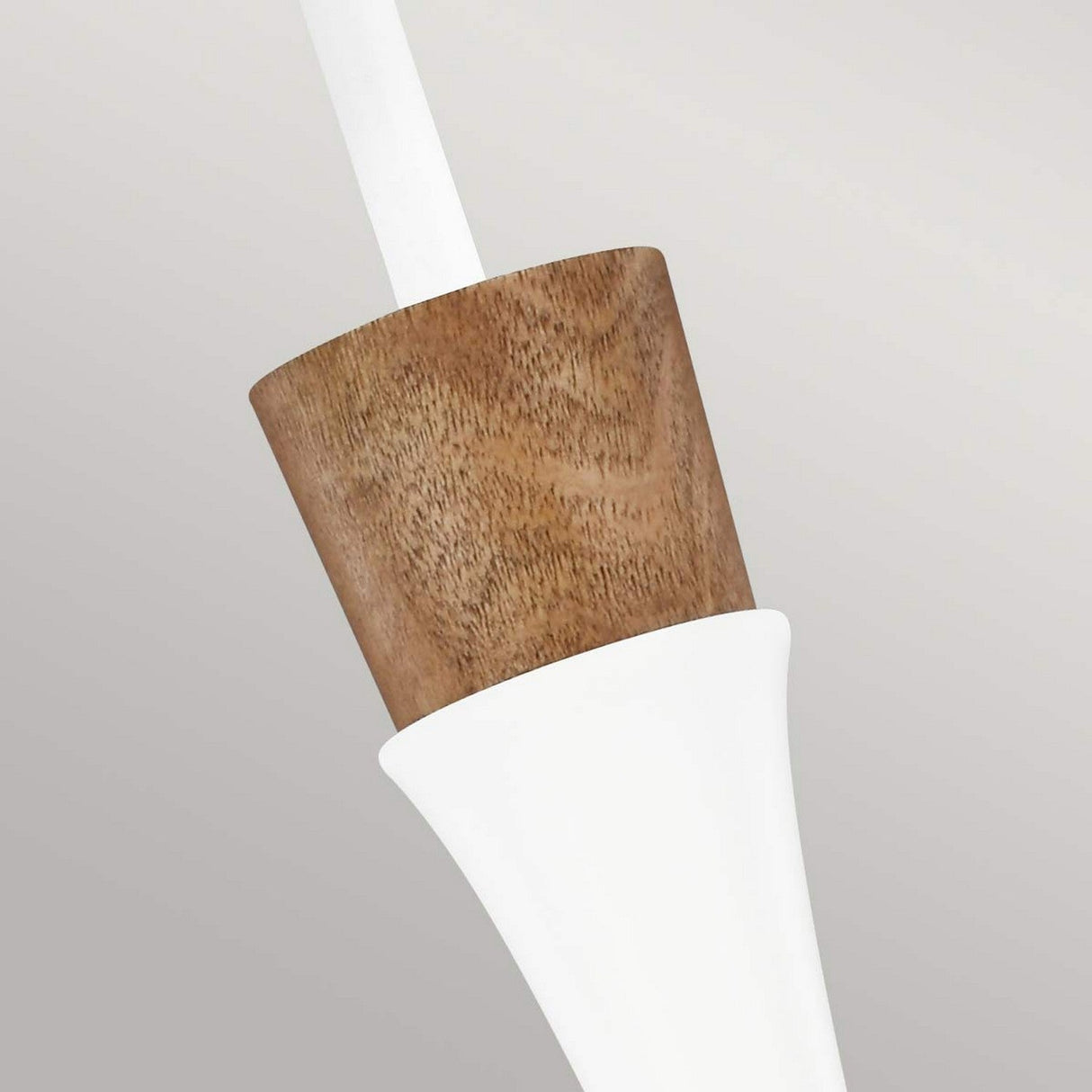 Close-up of the Darwin 1 Light Pendant - Matte White, showcasing its cone-shaped design. The top section, made from smooth wood, reflects urban style, while the sleek white bottom provides a striking contrast against the plain light gray background. Its adjustable height enhances practicality.