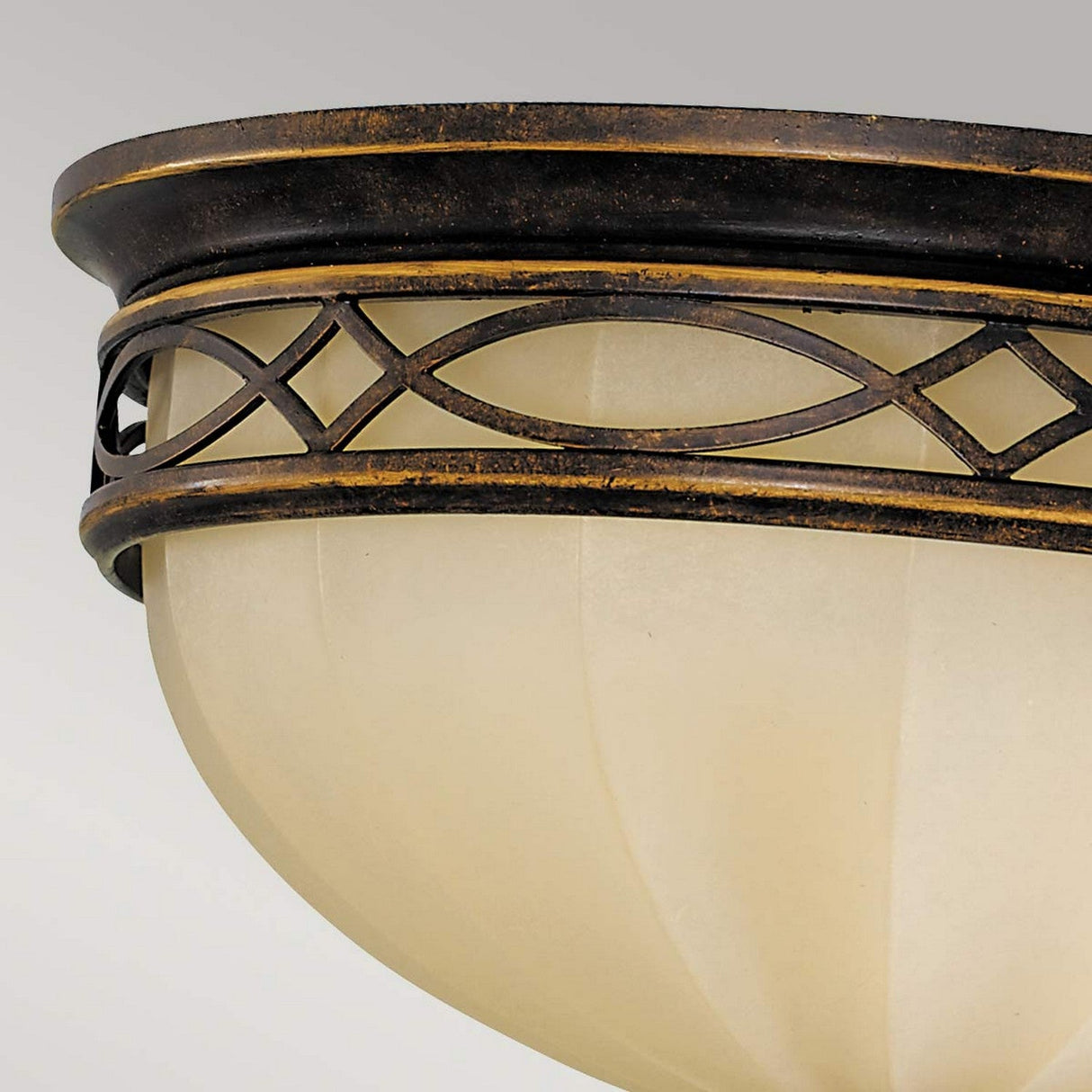 Close-up of the Drawing Room 3 Light Flush - Walnut, an elegant light fixture featuring a frosted dome-shaped glass shade. It boasts a decorative bronze metal trim with a crisscross pattern, reminiscent of Edwardian design, adding a touch of sophistication.