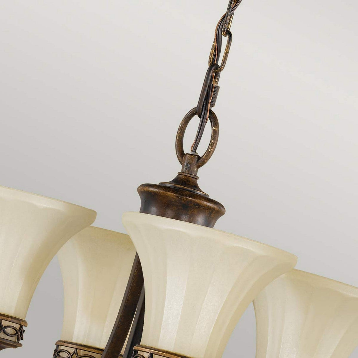 A close-up of the Drawing 4 Light Chandelier - Walnut captures the essence of Edwardian tradition, showcasing three downward-facing frosted glass shades connected to an ornate metal chain and central rod, all set against a neutral background.