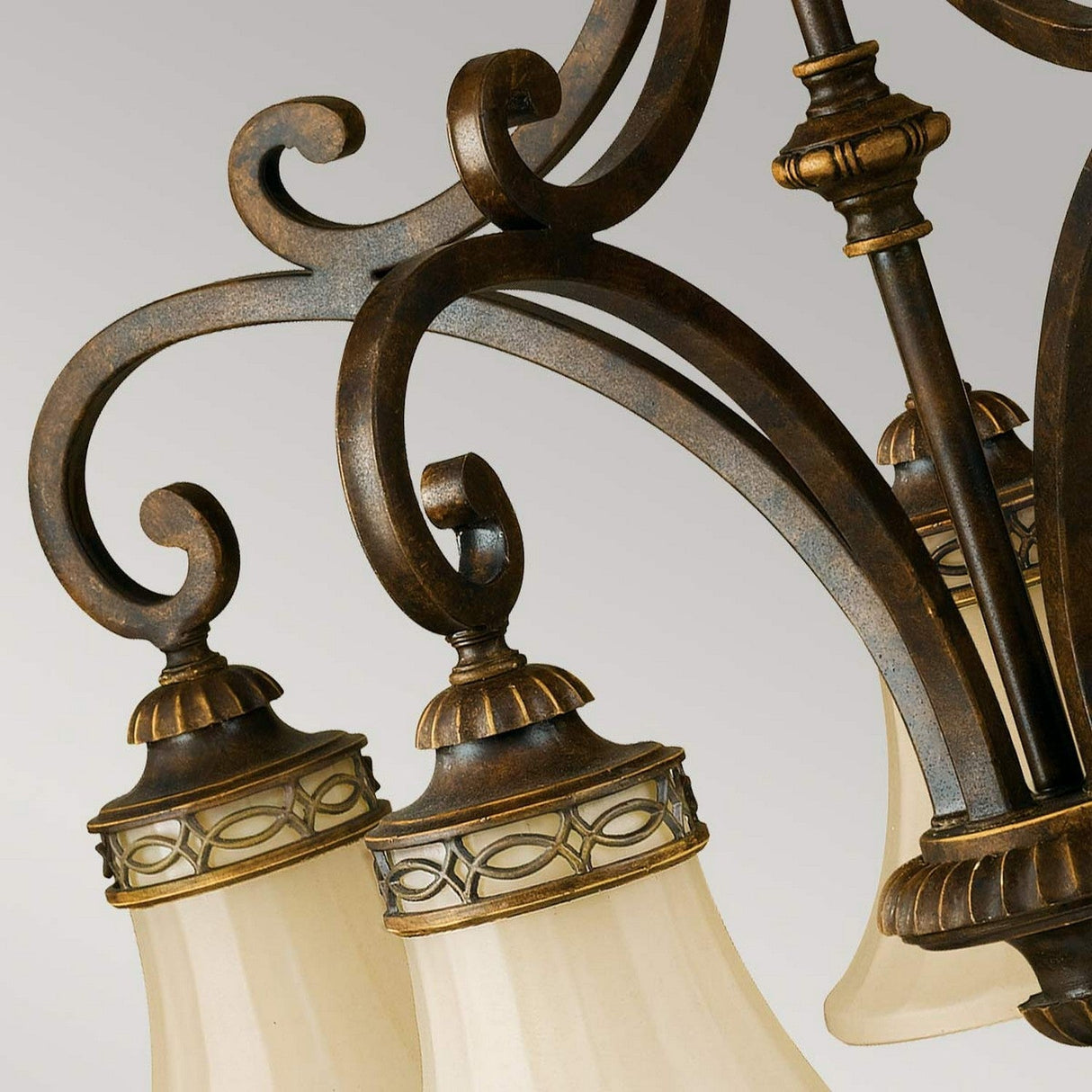 Close-up of the Drawing Room 5 Light Chandelier - Walnut, showcasing its ornate Edwardian charm with decorative scrollwork and three frosted glass lampshades complemented by brass accents, set against a neutral background.