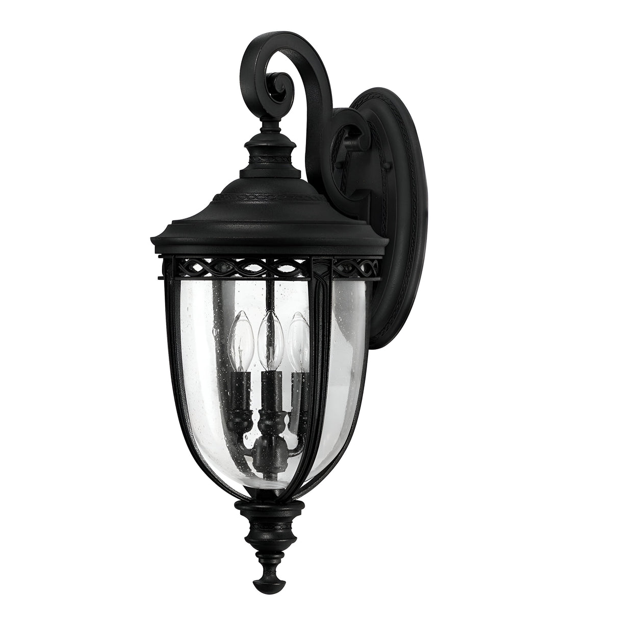 The English Bridle 3 Light Outdoor Large Wall Lantern in black boasts an intricate scroll design with a clear glass enclosure, housing three candle-shaped bulbs. It is mounted on a round base adorned with decorative detailing, enhanced by its sleek black finish for an elegant look.