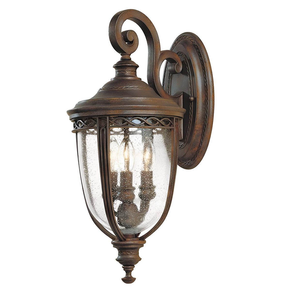 Close-up of an English Bridle 3 Light Outdoor Medium Wall Lantern in bronze, highlighting its vintage bronze finish and clear seeded glass panels. The lantern features decorative scrollwork with three candle-like bulbs inside.