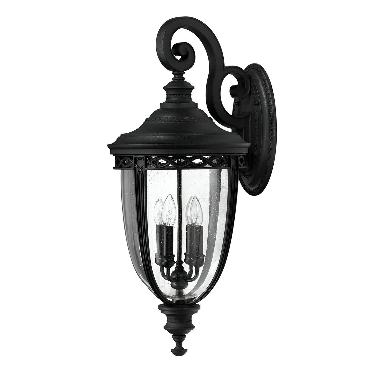 The English Bridle 4 Light Outdoor Extra Large Wall Lantern in black showcases an ornate design with clear glass panels and two candle-shaped bulbs. Its vintage appeal is accentuated by a decorative scroll at the top, offering a classic and elegant appearance.