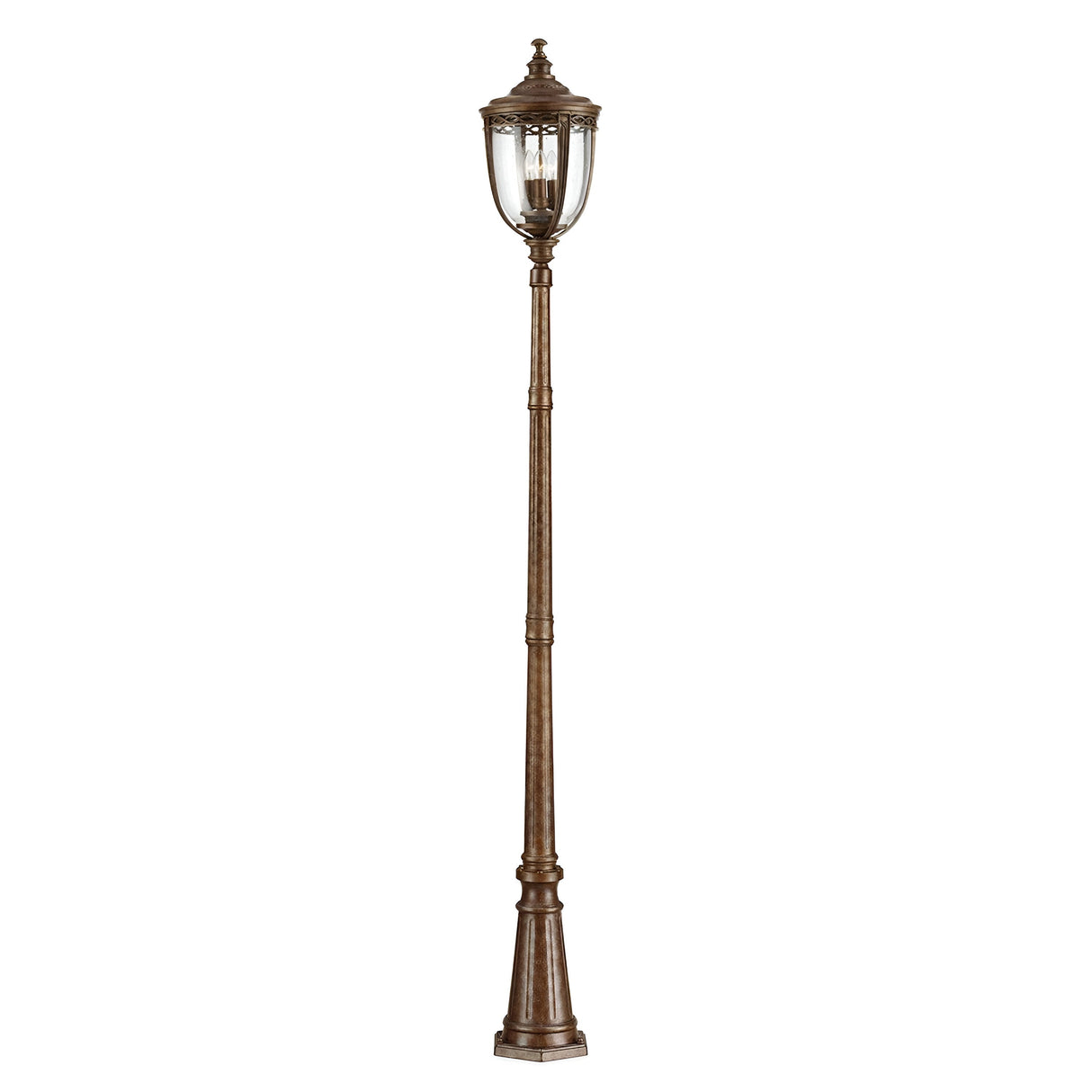 The English Bridle 3 Light Large Lamp Post - Bronze offers a vintage aesthetic with its tall, ornate post and clear seeded glass lantern, showcasing intricate metalwork in a luxurious British Bronze finish that enhances its timeless appeal.
