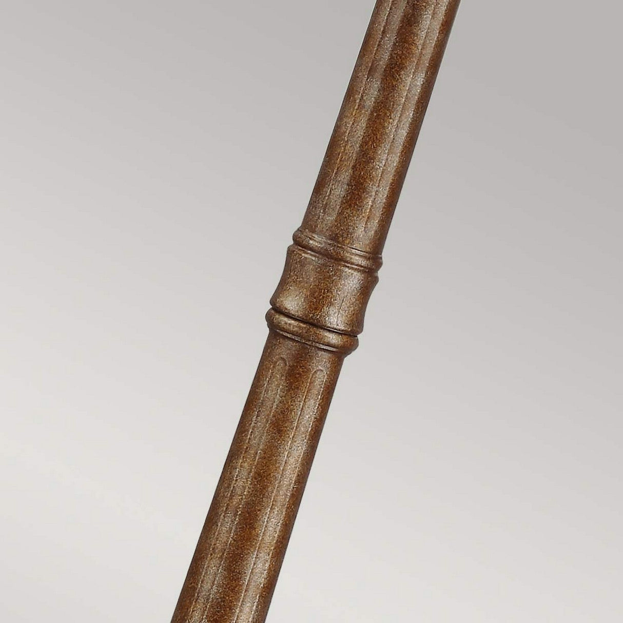 Close-up of a textured wooden pole or rod against a plain background. The pole, reminiscent of the English Bridle 3 Light Large Lamp Post - Bronze, features a ribbed design with a central ring accent, showcasing a natural brown finish that evokes the warmth of British Bronze.