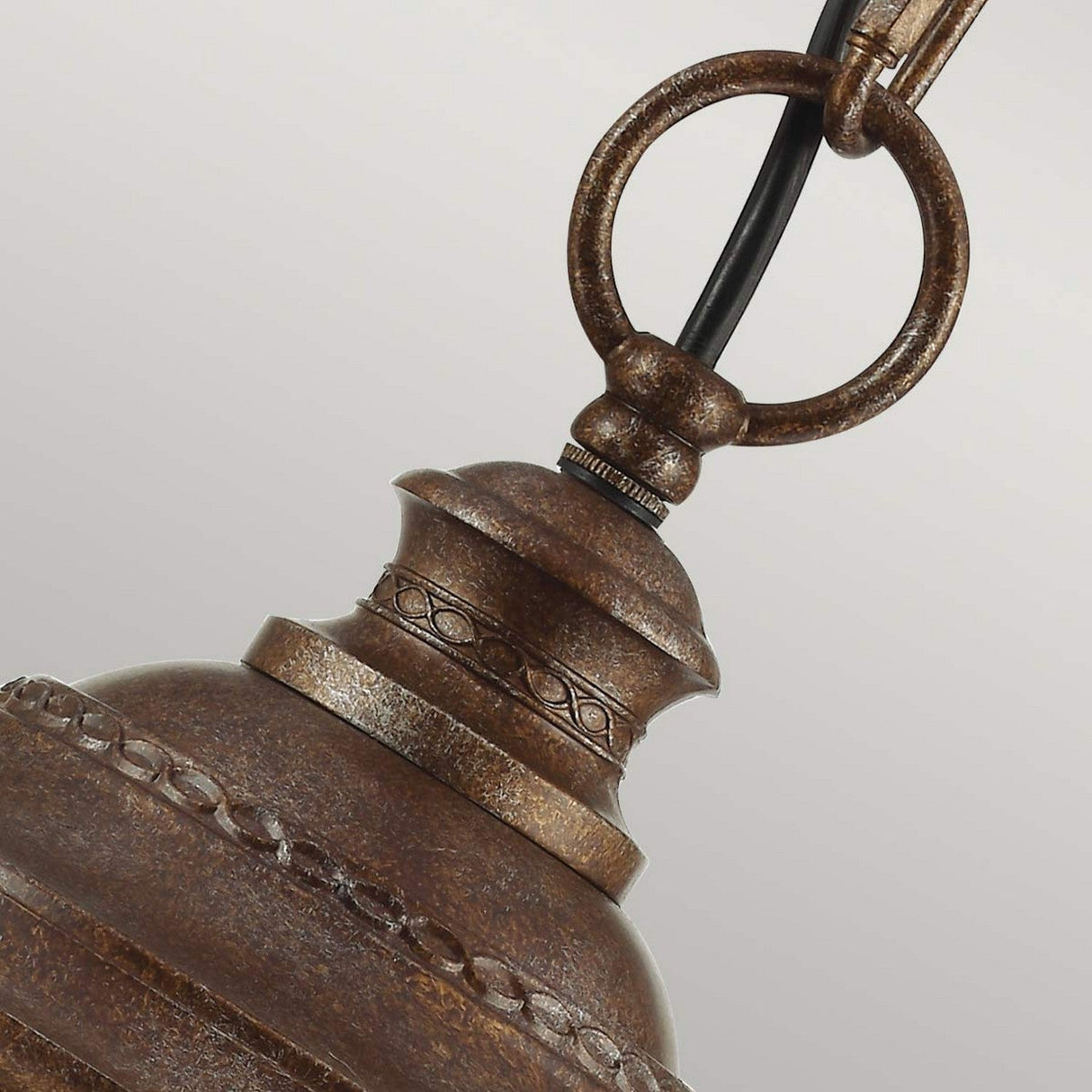 Close-up of the English Bridle 3 Light Outdoor Large Chain Lantern in a vintage-style design with a rustic British bronze finish. This piece features ornate decorative elements and a round attachment loop at the top, complemented by a visible black cord against a neutral gray background.
