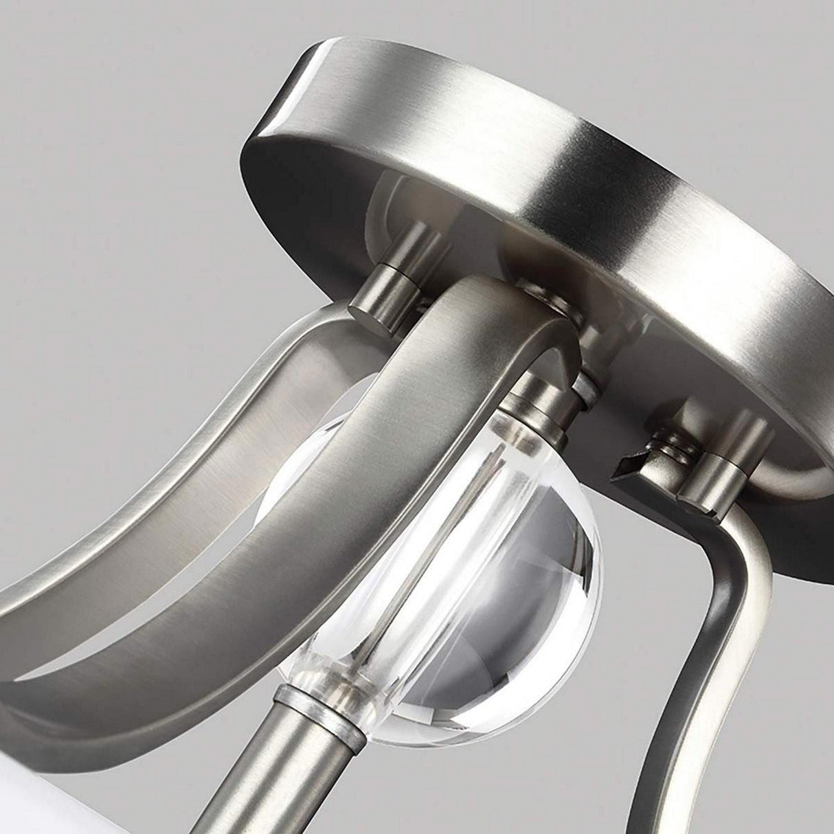 Close-up of the Evington 2 Light Semi Flush fixture, featuring a satin nickel finish and elegantly etched blown opal glass. This semi-flush design showcases sleek, curved metal arms that support a clear glass globe, beautifully set against a neutral background.