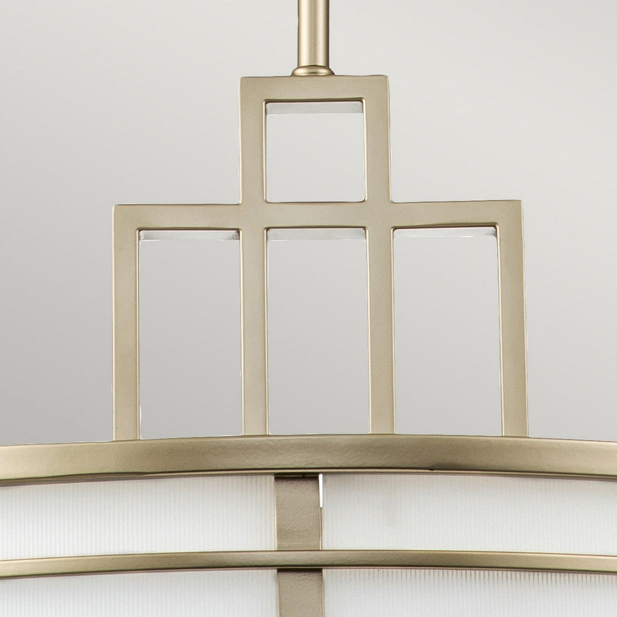 Close-up of the Fusion 3 Light Large Chandelier, showcasing its modern geometric design with rectangular shapes and a painted natural brass finish, complemented by amber ribbed glass, set against a light gray background.