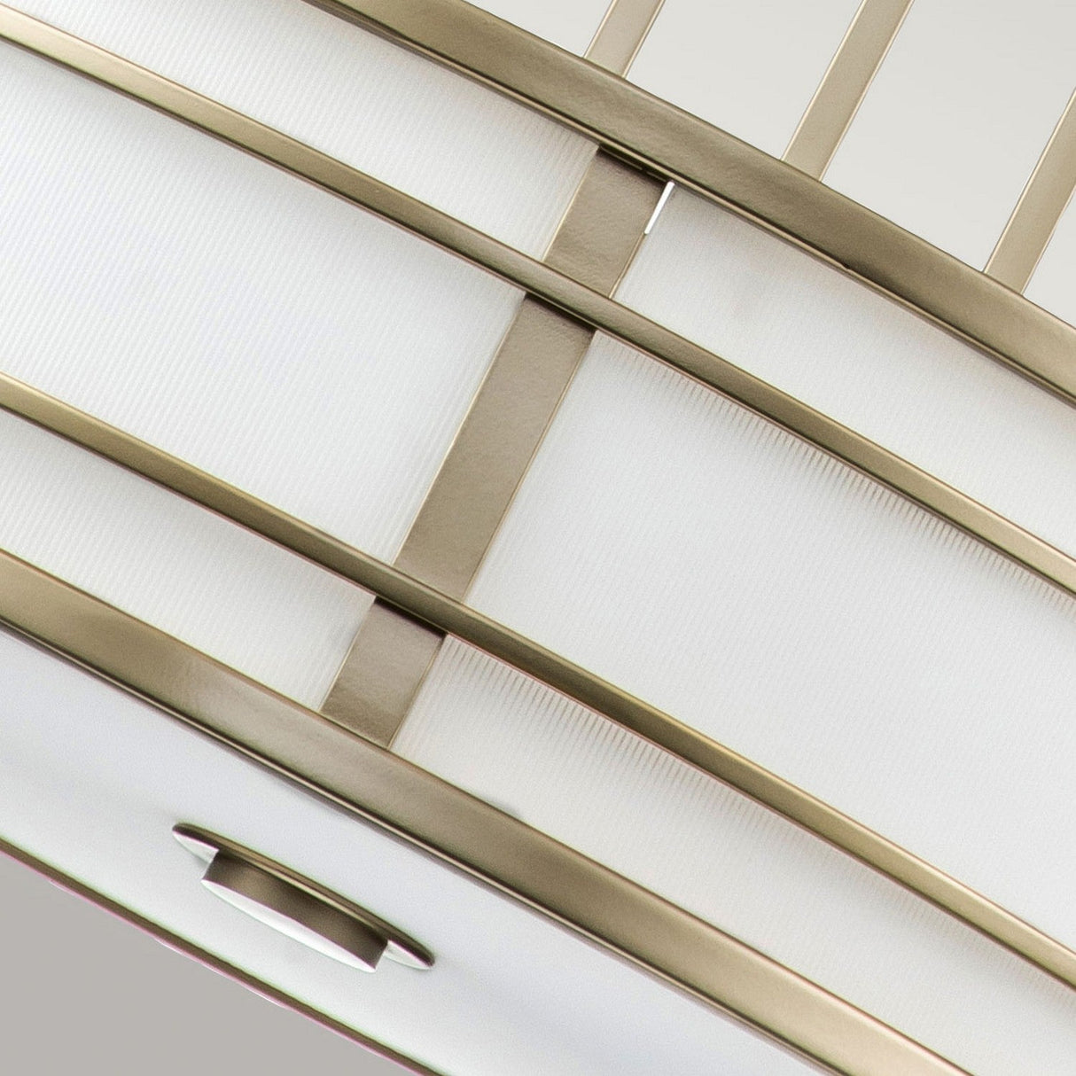 The Fusion 3 Light Large Chandelier in Painted Natural Brass showcases a modern design with curved silver metal accents and amber ribbed glass panels, offering a stylish and sleek appearance in close-up.