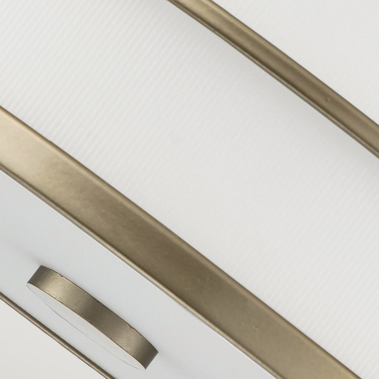 Close-up of the Fusion 3 Light Semi Flush - Painted Natural Brass, showcasing two parallel, curved metal bands encasing an amber ribbed glass shade, all centered around a circular metal fixture with a natural brass finish.