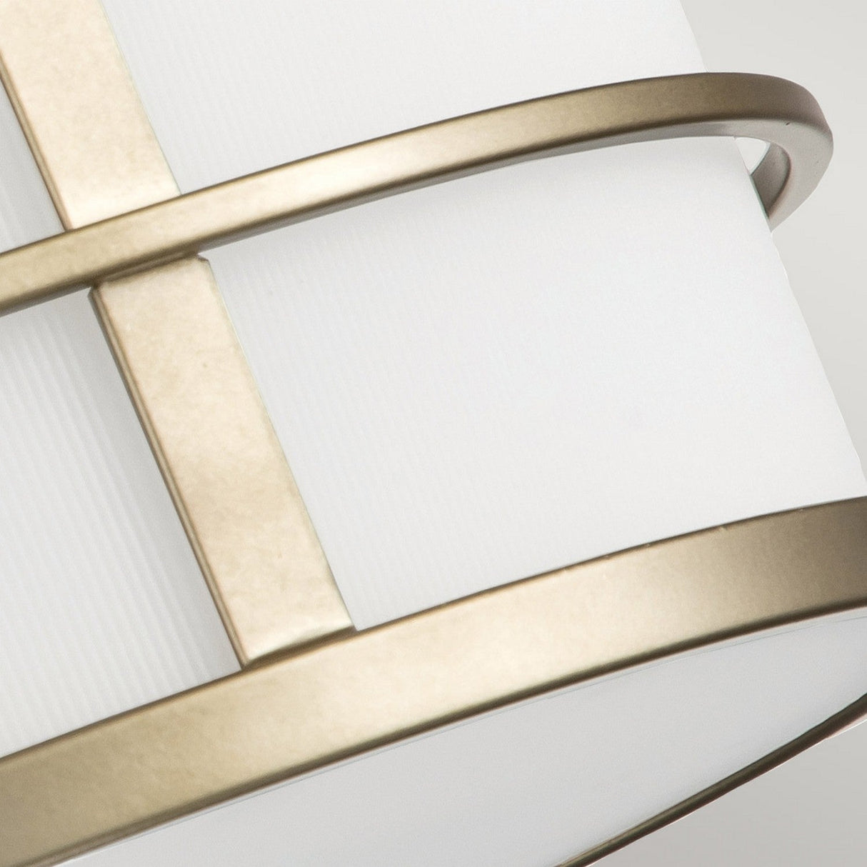 Close-up of the Fusion 3 Light Semi Flush, featuring a modern cylindrical white shade with brushed metal rings crossing it. The minimalist design showcases clean lines and a painted natural brass finish, offering a contemporary aesthetic.