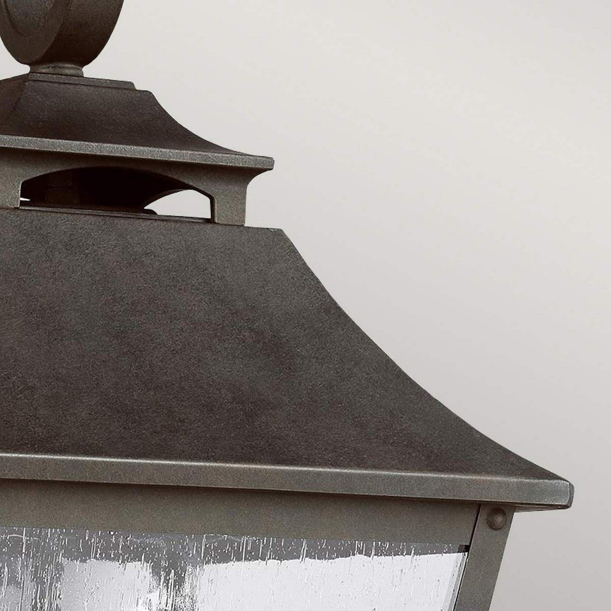 Close-up of the Galena 3 Light Outdoor Large Wall Lantern in black with a geometric design set against a light gray background. The image highlights the top half of the lantern, showcasing its textured metal surface and minimalistic style, evoking elegance typically seen in large wall lantern designs.