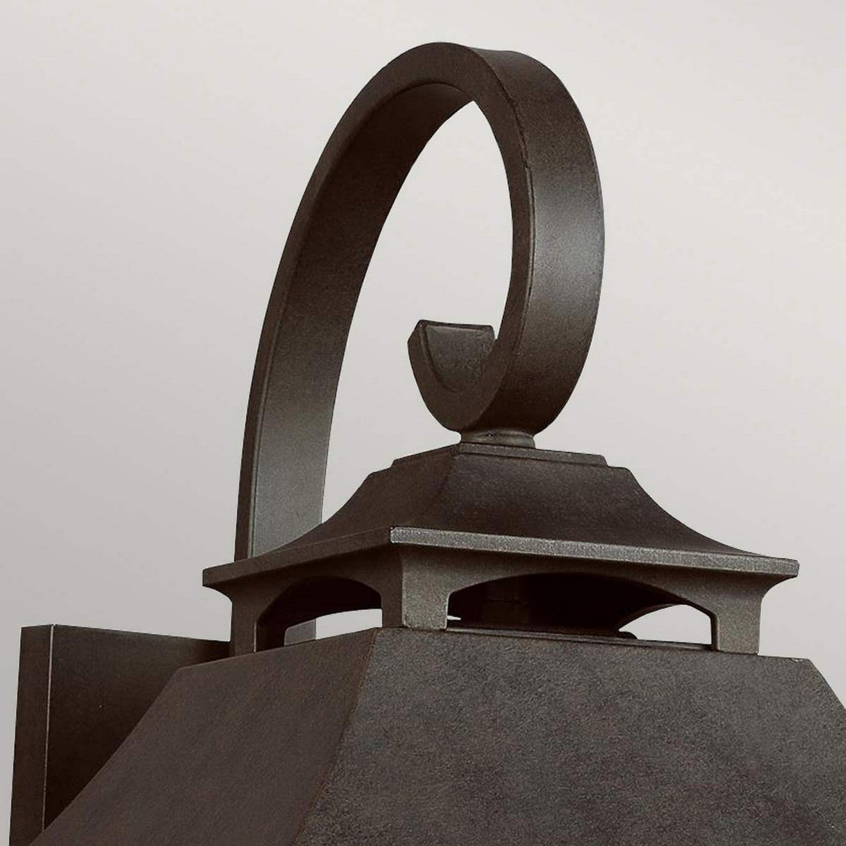 Close-up of the Galena 3 Light Outdoor Large Wall Lantern in grey, showcasing its dark metal construction and decorative curved handle on top. With its square base and textured finish, this outdoor wall lantern exudes vintage charm against a plain background.