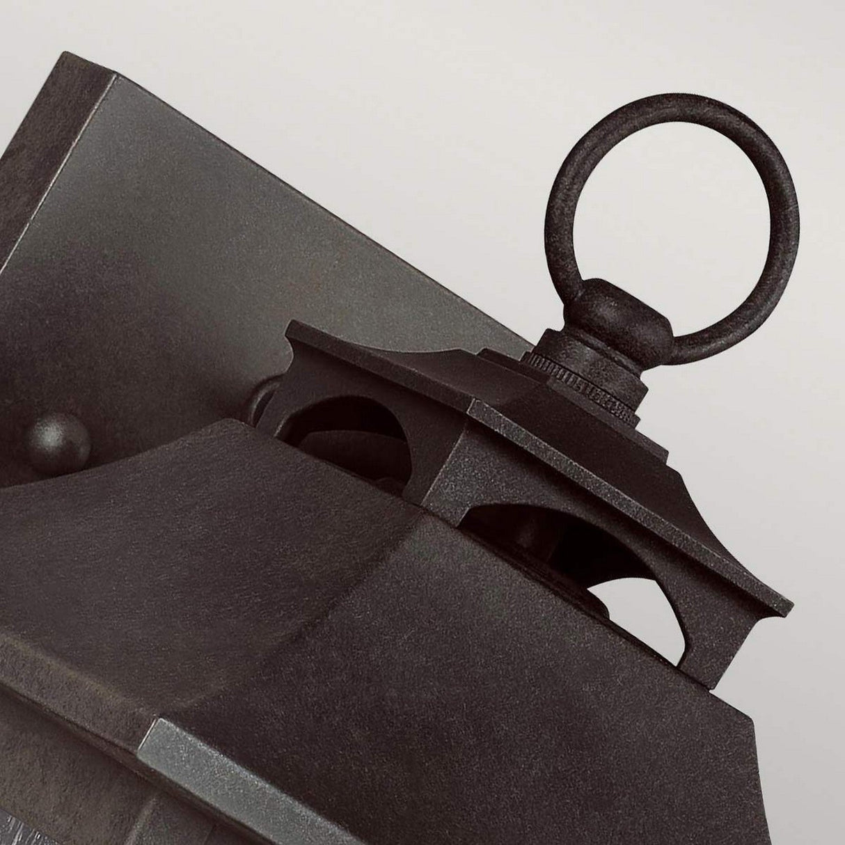 Close-up of a Galena 1 Light Outdoor Small Wall Lantern in grey, showcasing its black metal design with a square base and circular ring on top. This IP44-rated lantern features a traditional aesthetic with a smooth finish and charming seeded glass, set against a neutral background.