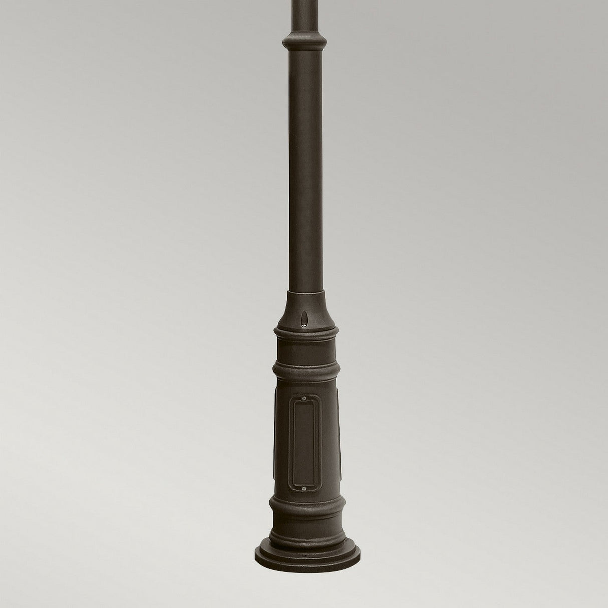 A close-up of the base of a dark-colored street lamp against a plain gray background. The cylindrical lamp post showcases decorative details near the bottom, reminiscent of the elegant design seen in outdoor lighting like the Galena 4 Light Lamp Post - Grey, with its charming seeded glass accents.