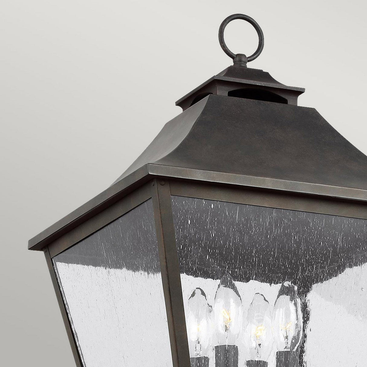 The Galena 4 Light Lamp Post - Grey showcases a vintage-style design with a dark metal frame and seeded glass panels. Inside, multiple candle-like bulbs add to its classic charm and timeless elegance, making it an exquisite piece of outdoor lighting.