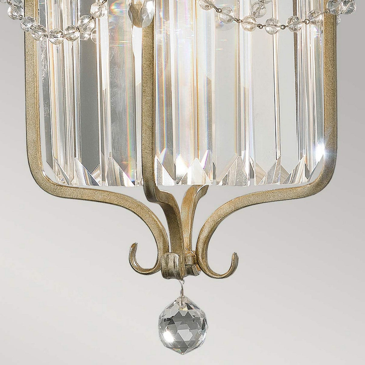 A close-up reveals the refined design of the Gianna 1 Light Pendant in Gilded Silver, featuring faceted glass panels and crystal embellishments. The gold-toned metal adds an air of sophistication, with delicate chains that gracefully connect each element, casting gentle reflections and exuding timeless elegance.