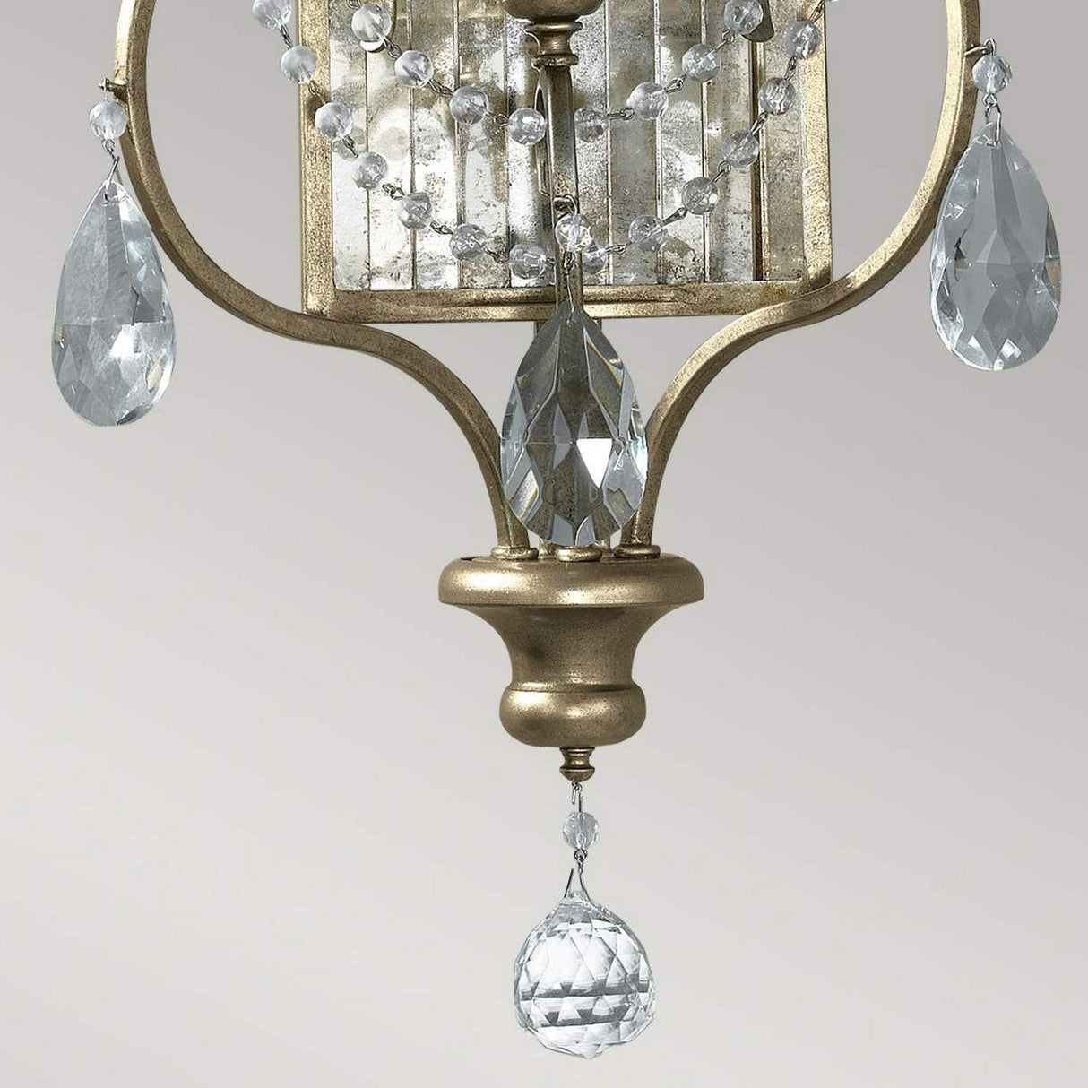 A close-up of the Gianna 3 Light Wall Light - Gilded Silver highlights its hand-cut crystals and teardrop-shaped pendants, elegantly arranged in an ornate gilded silver frame that beautifully reflects light against a neutral backdrop.