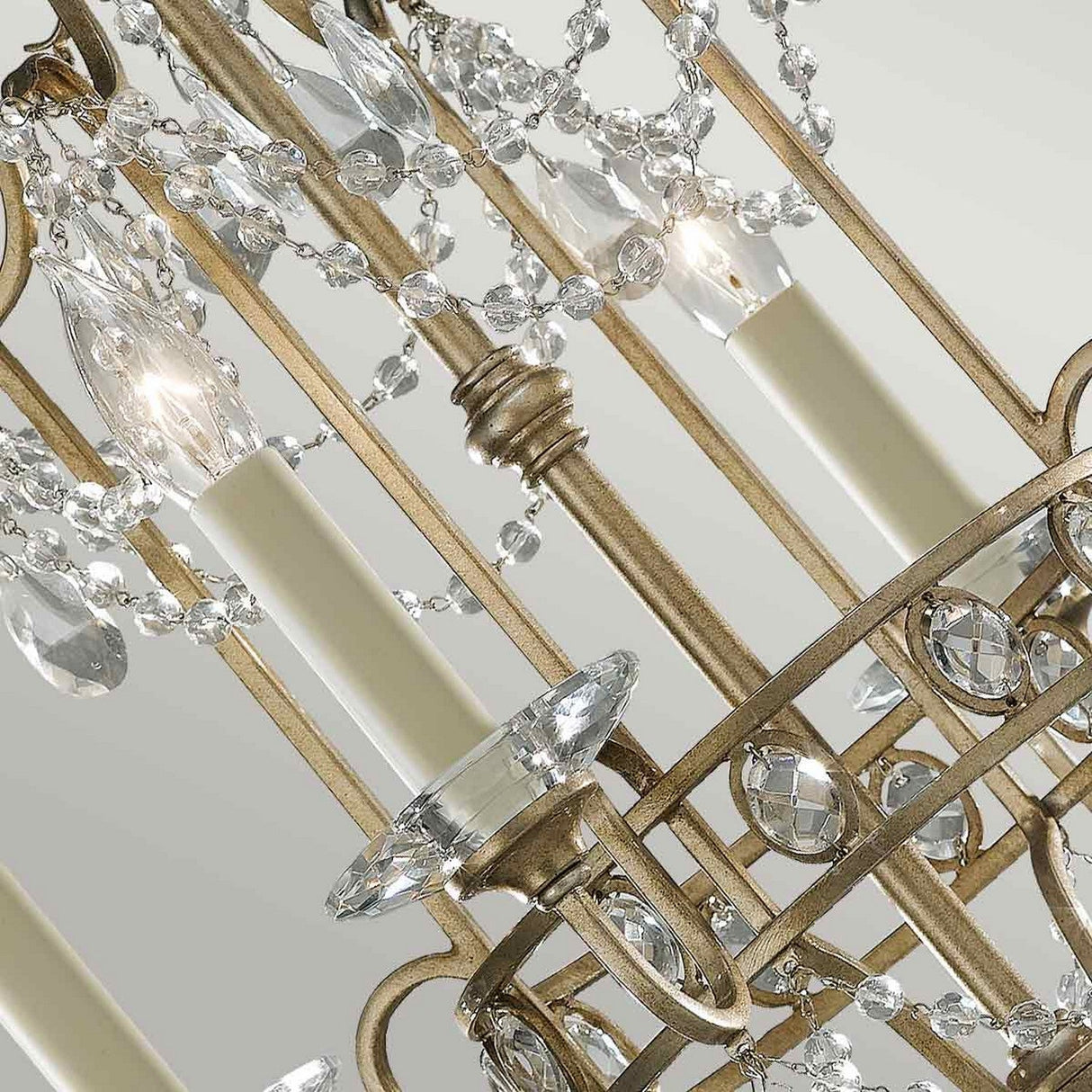 Close-up of the Gianna 4 Light Chandelier - Gilded Silver, an elegant piece showcasing Italian design with hand-cut crystal embellishments and candle-like bulb holders on a metallic silver frame. The intricate design features hanging crystal pendants against a neutral background.