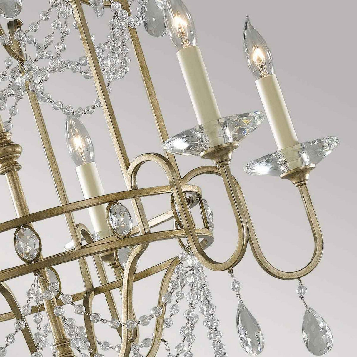 Close-up of the Gianna 6 Light Chandelier - Gilded Silver, showcasing four unlit candle-style bulbs with intricate metal arms adorned in a gilded silver finish, draped with hand-cut crystals. The chandelier's metallic structure exudes a subtle antique charm, beautifully contrasted against a neutral background.