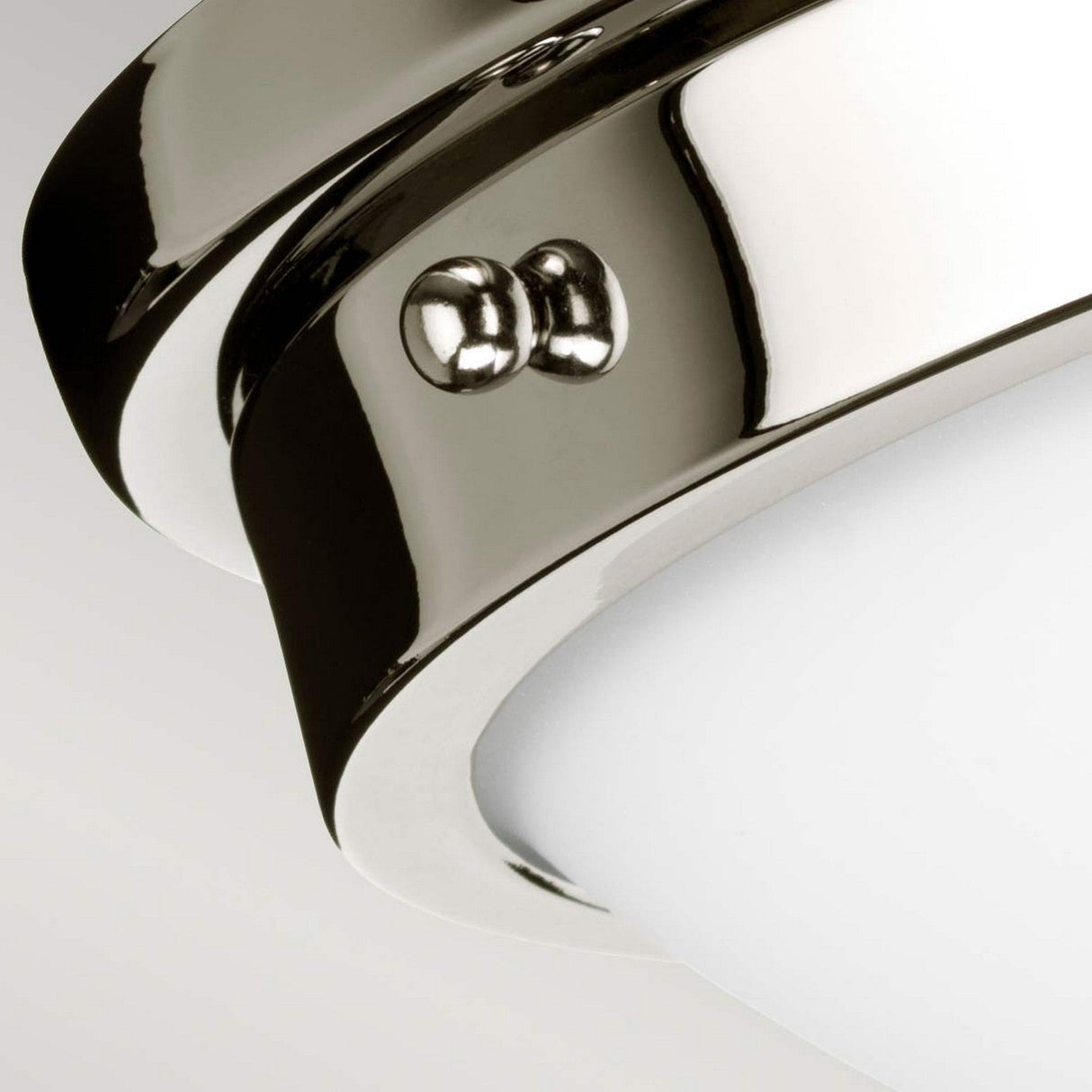 Close-up of the Gravity 2 Light Flush in polished nickel, featuring sleek, reflective surfaces and a white, opaque diffuser. This minimalist design is accentuated by two decorative screws on the side, enhancing its modern aesthetic.