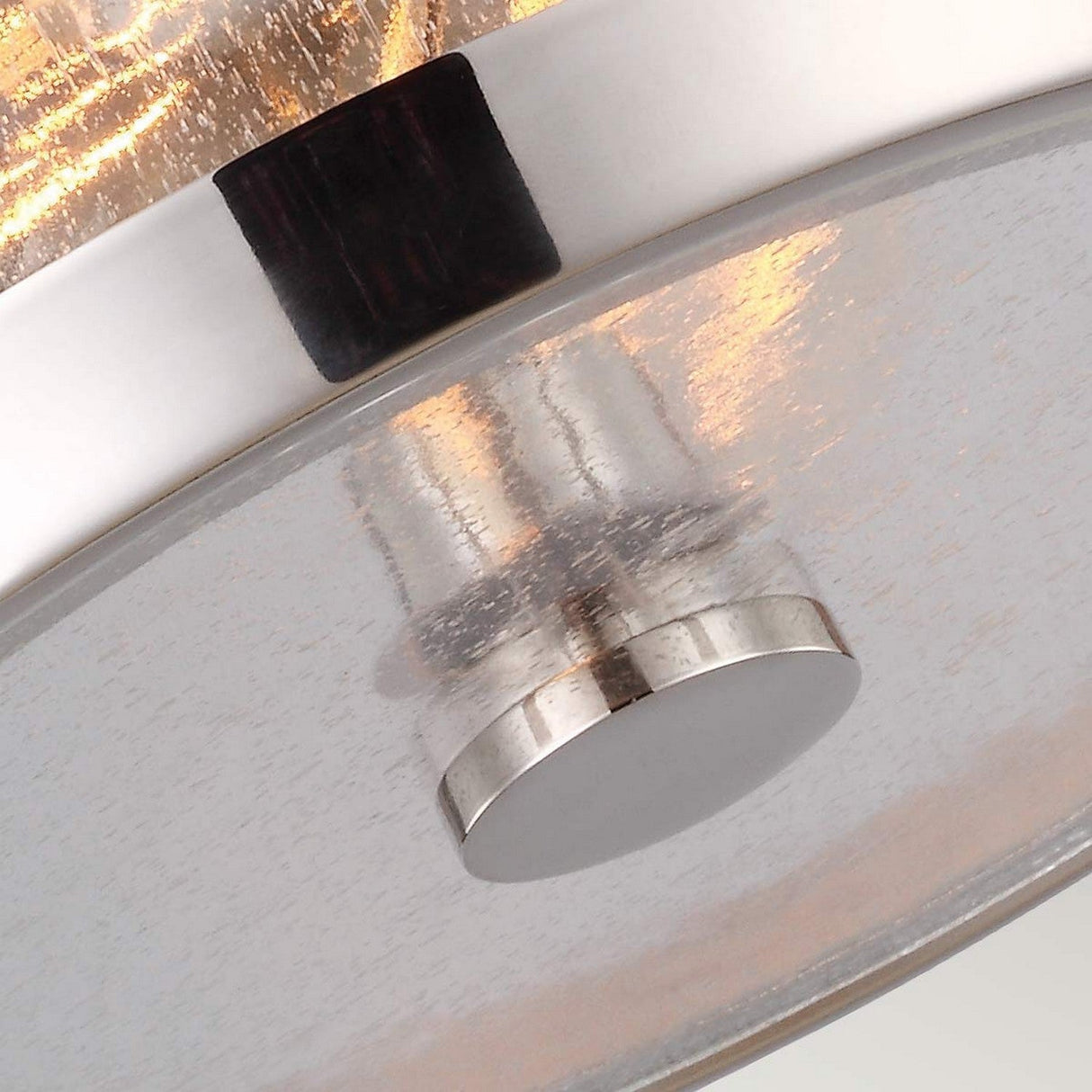 Detailed view of the Harrow 2 Light Flush - Polished Nickel fixture, featuring a modern design with a curved, translucent seeded glass cover and metal accents. Through the glass, a bright bulb creates a warm glow, complementing its sleek polished nickel finish.