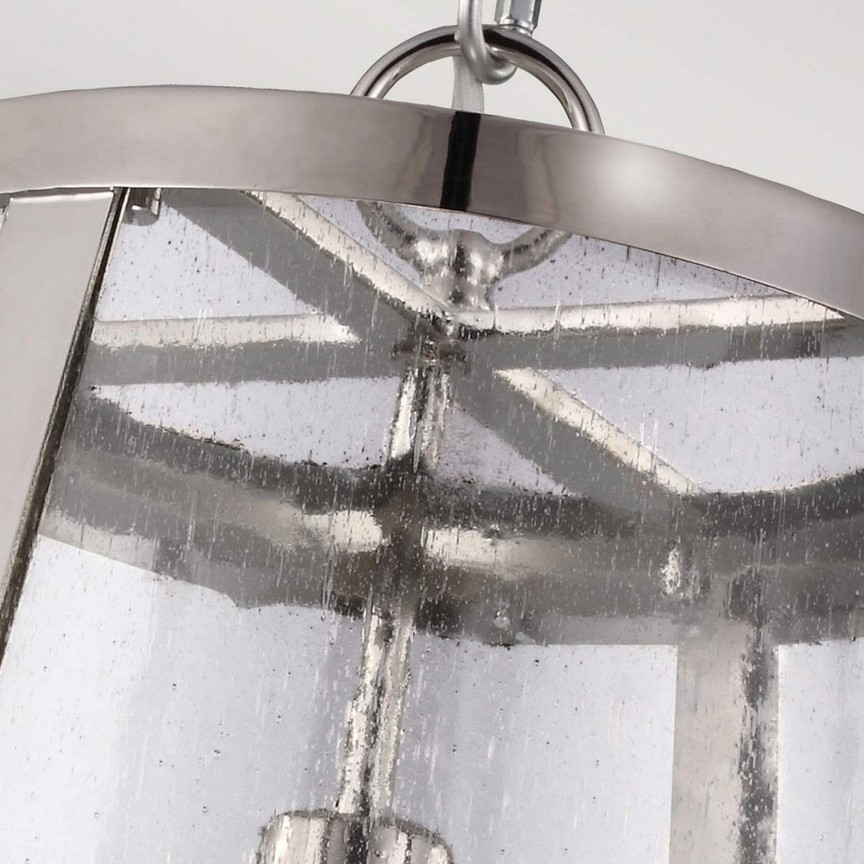 Close-up of the Harrow 1 Light Medium Pendant, featuring a polished nickel frame and clear seeded glass panels. This modern chandelier highlights intricate metalwork and is elegantly suspended from the ceiling with visible connecting rings.