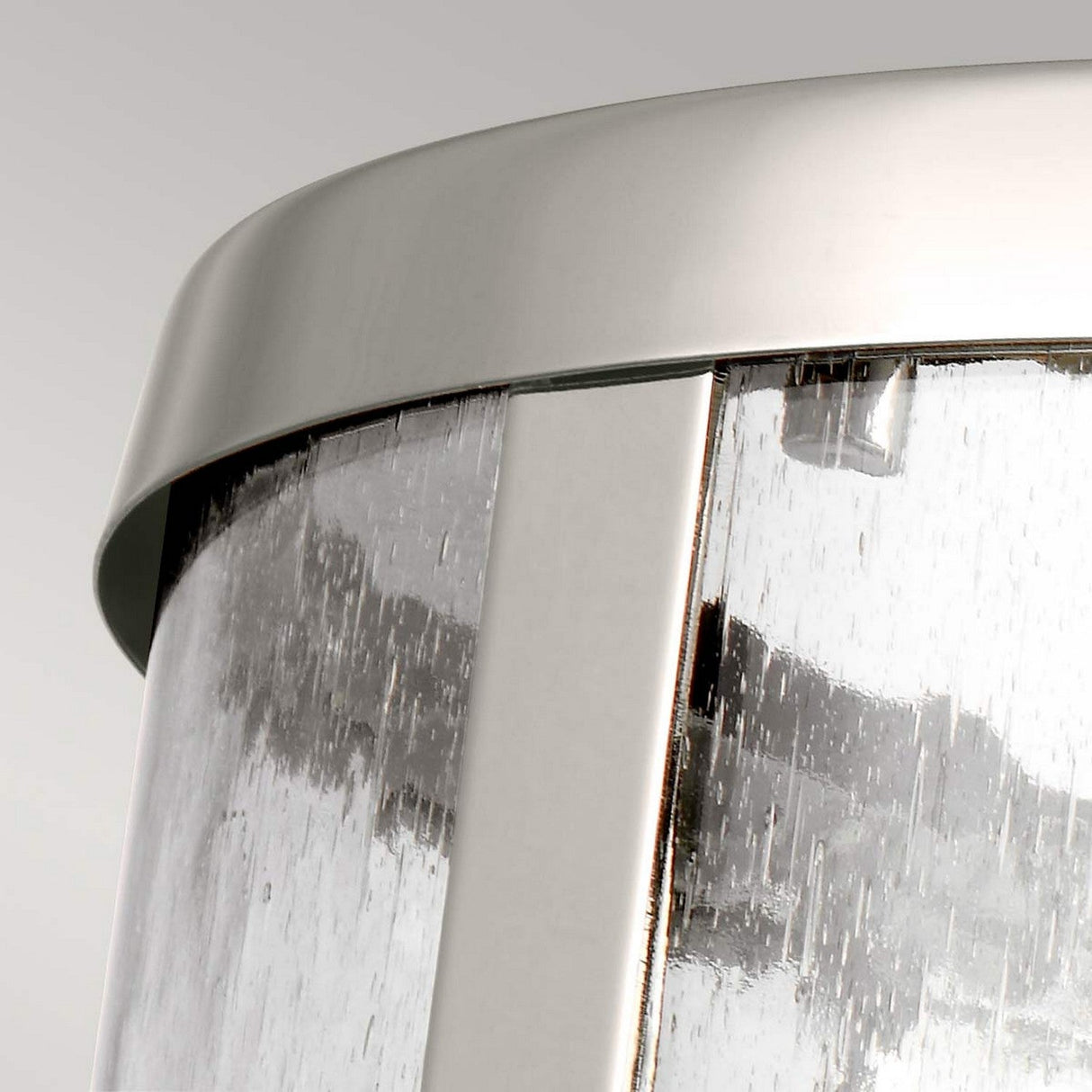 Close-up of the Harrow 1 Light Small Pendant in polished nickel, featuring a sleek metal frame and clear seeded glass. The light streams through the glass surface, creating a textured effect against a neutral, light-colored background.