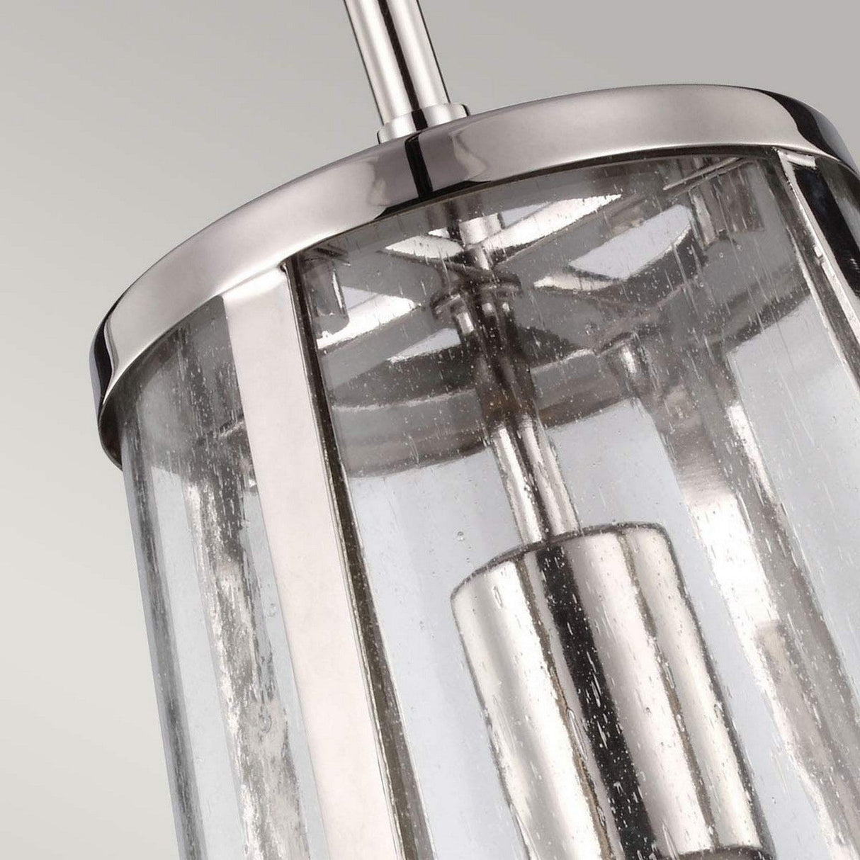 Close-up of the Harrow 1 Light Small Pendant in Polished Nickel, featuring a modern design with a cylindrical clear seeded glass shade. Inside, a metallic cylindrical fixture stands out, showcasing the lighting design against a neutral background.