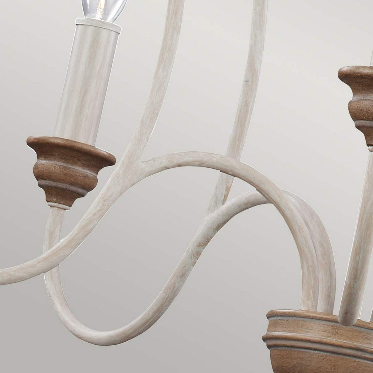 A detailed view of the Hartsville 5 Light Chandelier in Chalk Washed and Beachwood, showcasing its light wood and metal curved arms with a candle-style bulb holder. The natural wood finish enhances its rustic charm and farmhouse-inspired design, offering an elegant and timeless look against a neutral backdrop.