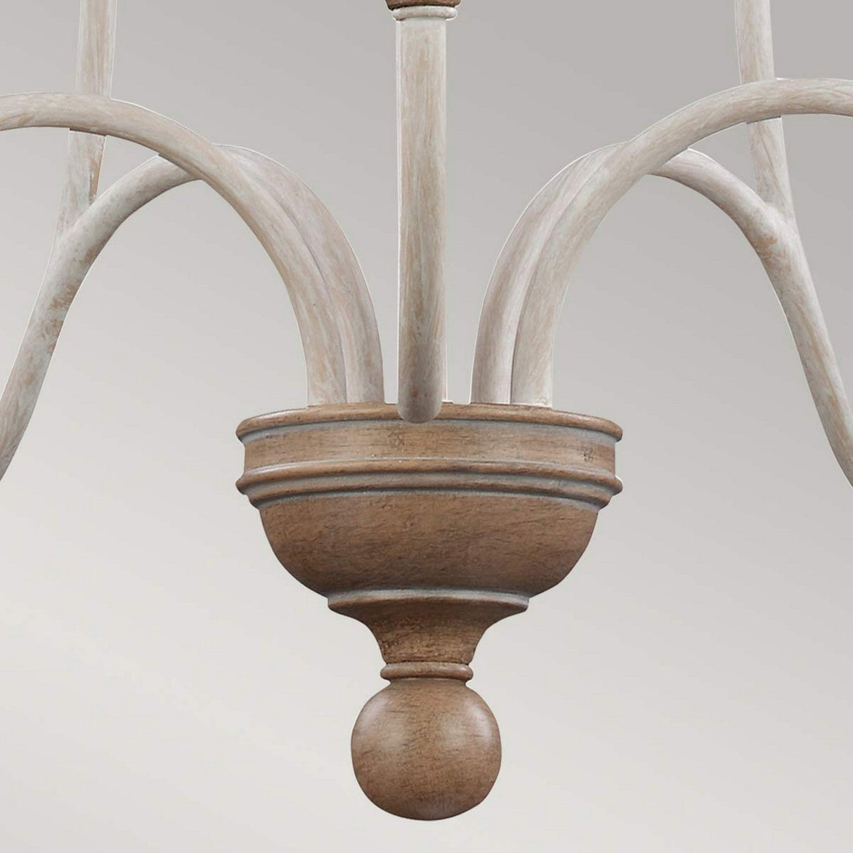 Close-up of the Hartsville 5 Light Chandelier - Chalk Washed/Beachwood, showcasing a rustic charm with its farmhouse-inspired design. It boasts curved, whitewashed metal arms and a central wooden decorative element with a rounded tip. The background is a plain, light gray.