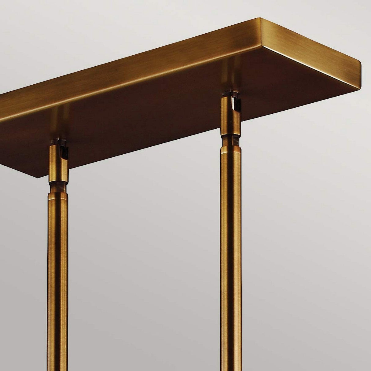 A minimalist, modern table featuring a rectangular aged brass top and two slender cylindrical legs against a plain background. Its clean lines and metallic finish exude an elegant, contemporary aesthetic that mirrors the timeless allure of the Hobson 3 Light Island Light in Aged Brass.