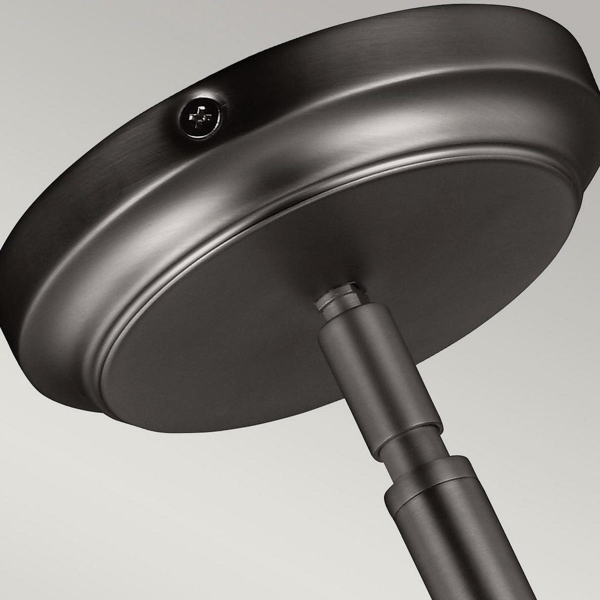 A close-up of the Hobson 1 Light Medium Pendant in satin nickel shows its metallic, circular ceiling mount with a cylindrical rod, highlighting an industrial-inspired lighting design. Set against a neutral background, this modern fixture features a visible screw on the rim.