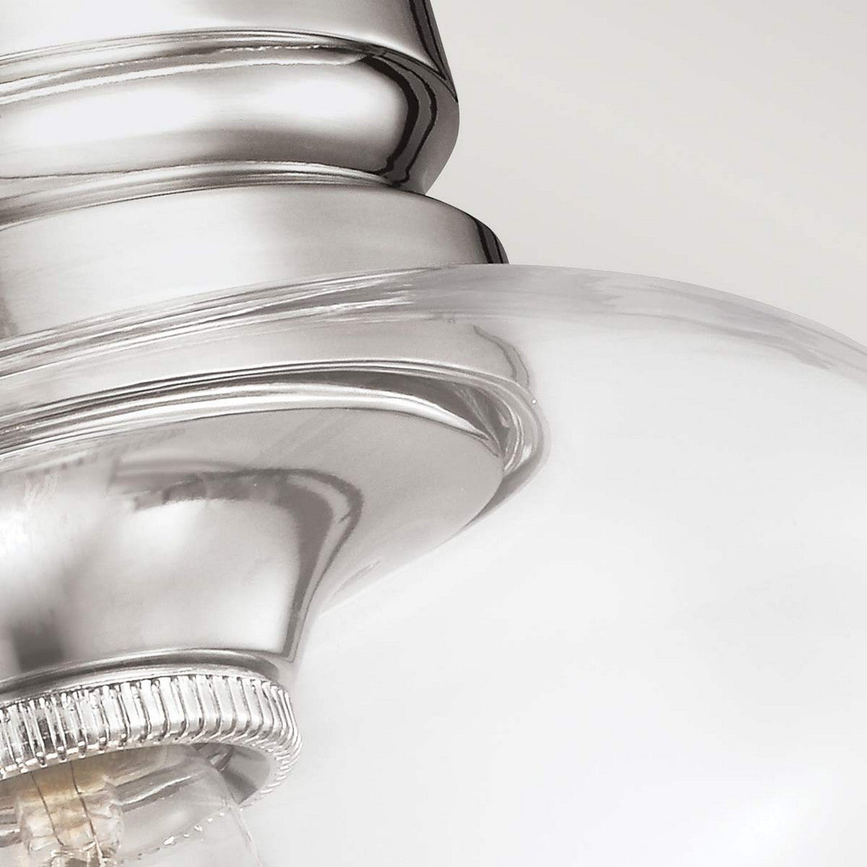 Close-up of the Hounslow 1 Light Flush in a polished nickel finish. This light fixture boasts a brushed metal and clear glass shade, with a curved metal base leading into a clear glass globe, offering a modern and sleek aesthetic. The polished nickel finish perfectly accentuates the smooth textures and reflective surfaces.