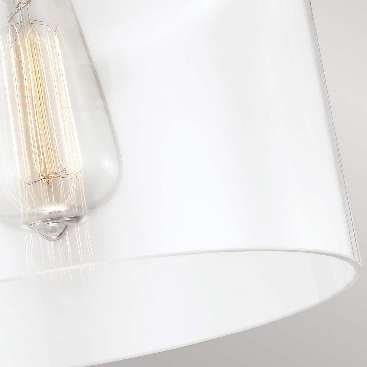 A close-up of the Hounslow 1 Light Flush - Polished Nickel pendant showcases the visible filament bulb inside, emphasizing its sleek design and clear glass shade details. The polished nickel elements stand out against a neutral background.