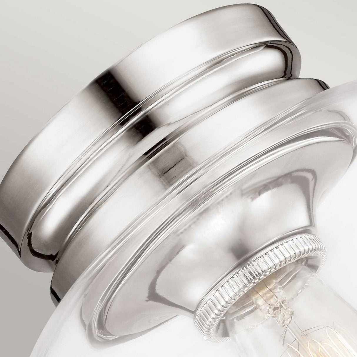 Close-up image of the Hounslow 1 Light Flush in a polished nickel finish. This elegantly designed ceiling light fixture features a curved shape and a clear glass shade that encases a light bulb, set against a neutral grey background.