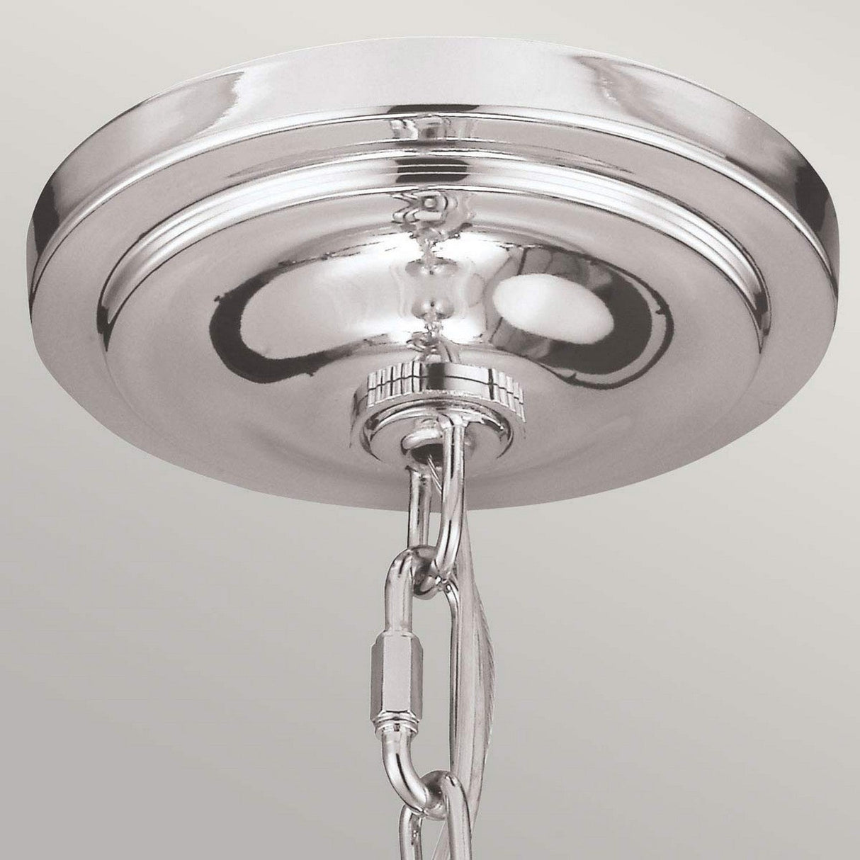 A close-up of the Hounslow 1 Light Pendant in polished nickel reveals a shiny, metallic ceiling canopy with an attached chain, suspended against a light-colored background. The pendant's surface reflects light, enhancing its sleek design and perfectly complementing the elegance of its clear glass shade.