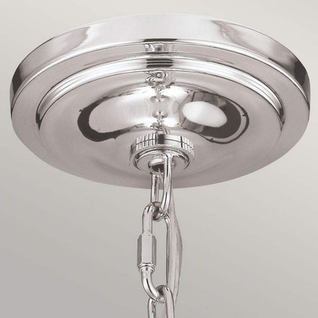 A close-up of the Hounslow 1 Light Pendant in polished nickel reveals a shiny, metallic ceiling canopy with an attached chain, suspended against a light-colored background. The pendant's surface reflects light, enhancing its sleek design and perfectly complementing the elegance of its clear glass shade.