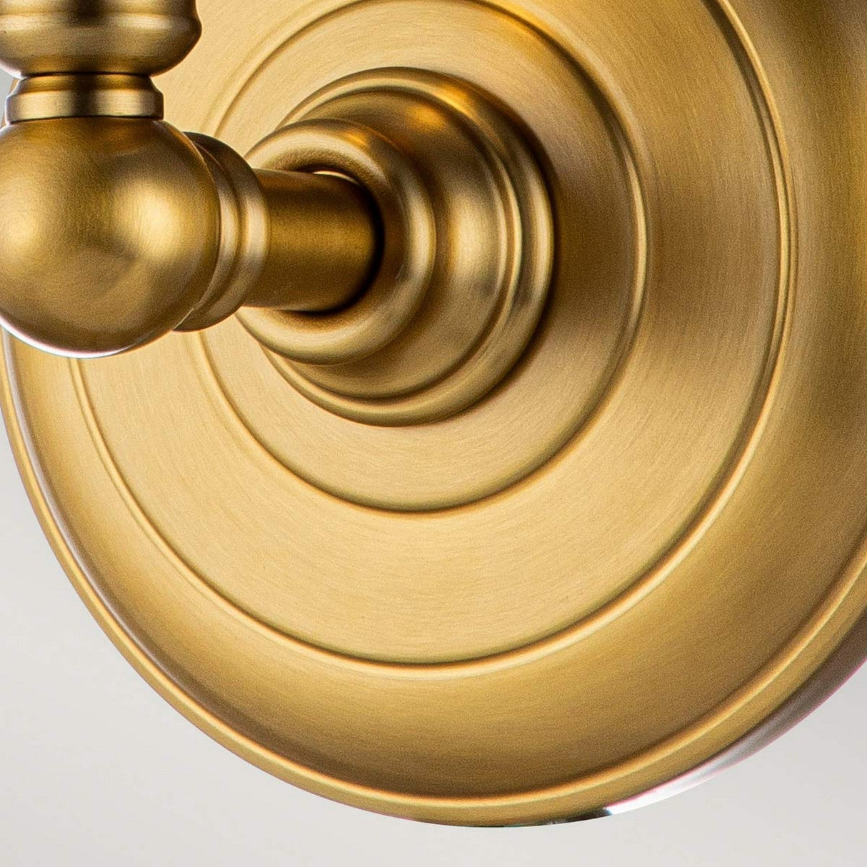 Close-up of the Huguenot Lake 1 Light Wall Light in burnished brass, featuring a circular plate design and decorative detailing. The brushed finish softly reflects light, exuding a warm and elegant appearance.