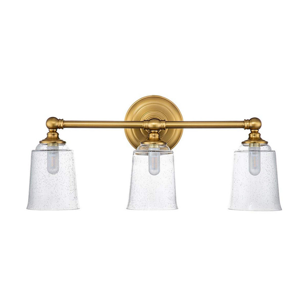 The Huguenot Lake 3 Light Wall Light in burnished brass is a vanity fixture that elegantly combines colonial and modern styles. It features three arms with clear, seeded glass shades, showcasing visible bulbs within. The central mount attaches to a round base, adding timeless elegance to any space.