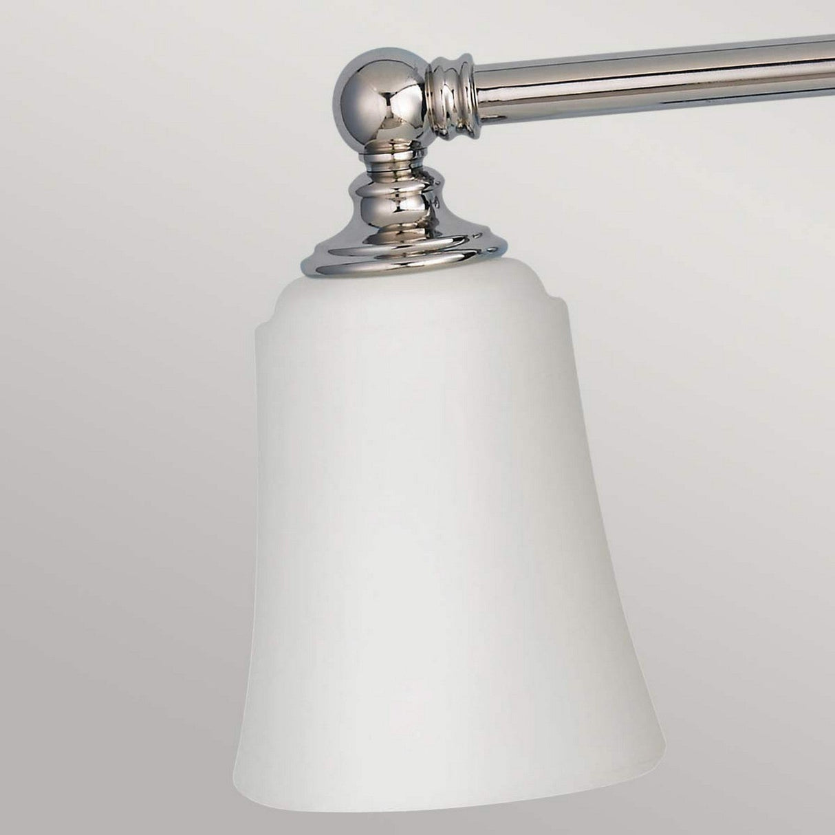 A close-up of the Huguenot Lake 3 Light Wall Light in polished chrome, featuring a frosted glass shade, mounted against a light gray background. This sleek light fixture highlights a decorative, rounded base with a straight arm extending outward.