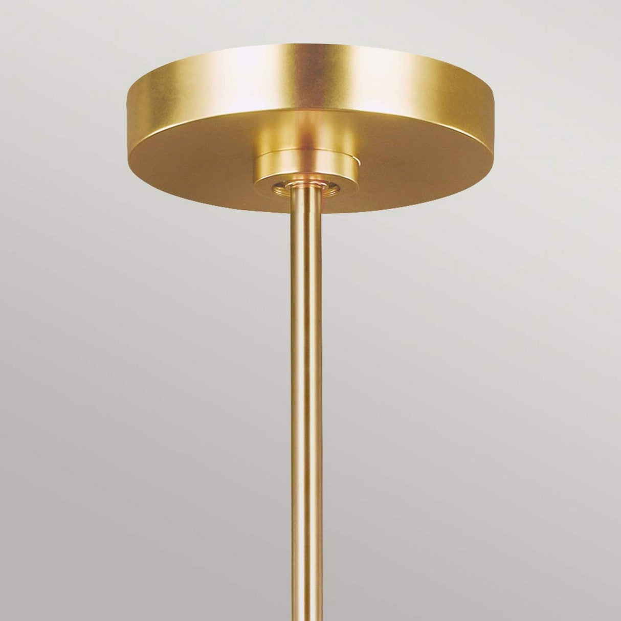 A gold ceiling light fixture with a cylindrical base and a round, flat canopy against a light gray background showcases an Art Deco design. Made from burnished brass, this piece reflects the sophistication of the Jax 10 Light Chandelier - Burnished Brass.