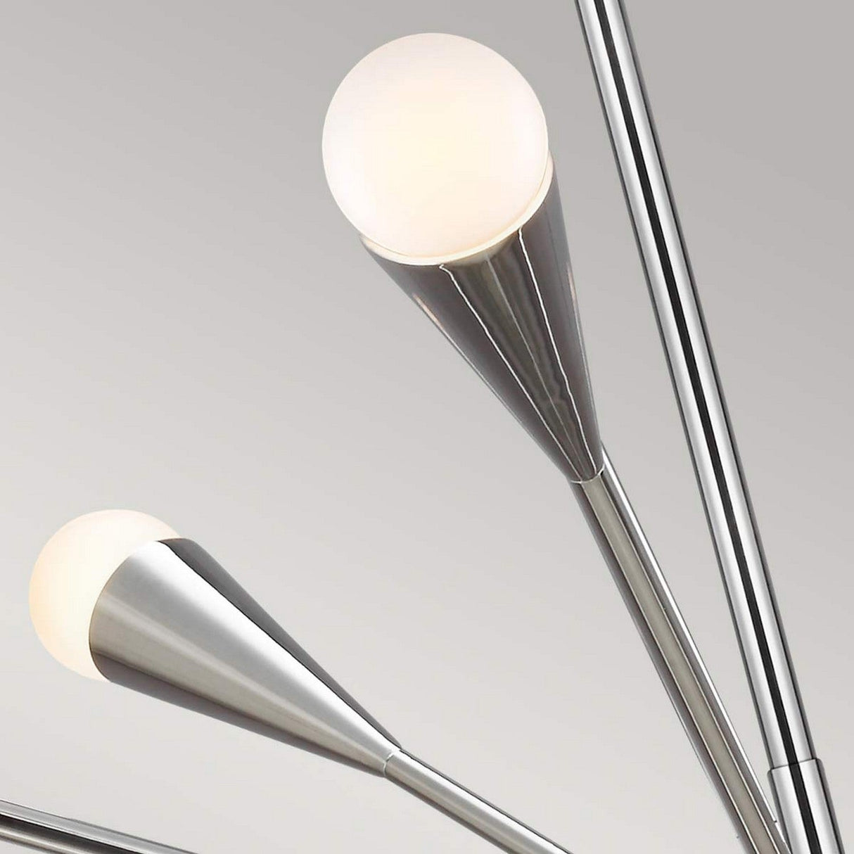 Close-up of the Jax 10 Light Chandelier in polished nickel, showcasing two metallic cone-shaped arms each adorned with a round, frosted white bulb. The stylish and minimalist design contributes to a contemporary aesthetic against a neutral background.