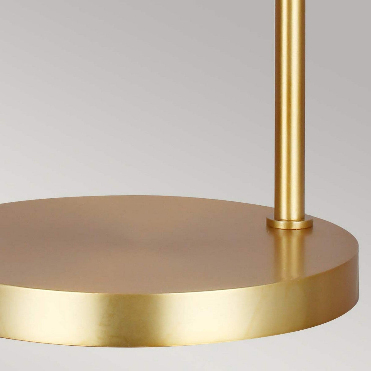 Close-up of the Joan 1 Light Table Lamp with a burnished brass finish. The image shows part of the cylindrical base and a vertical rod against a light gray background.