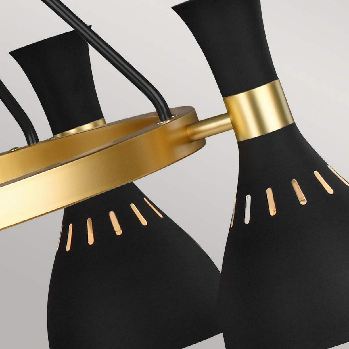 Close-up of the Joan 5 Light Chandelier - Midnight Black/Burnished Brass, highlighting three cone-shaped lampshades in midnight black with gold accents and small cut-out slits, all mounted on a circular burnished brass frame.