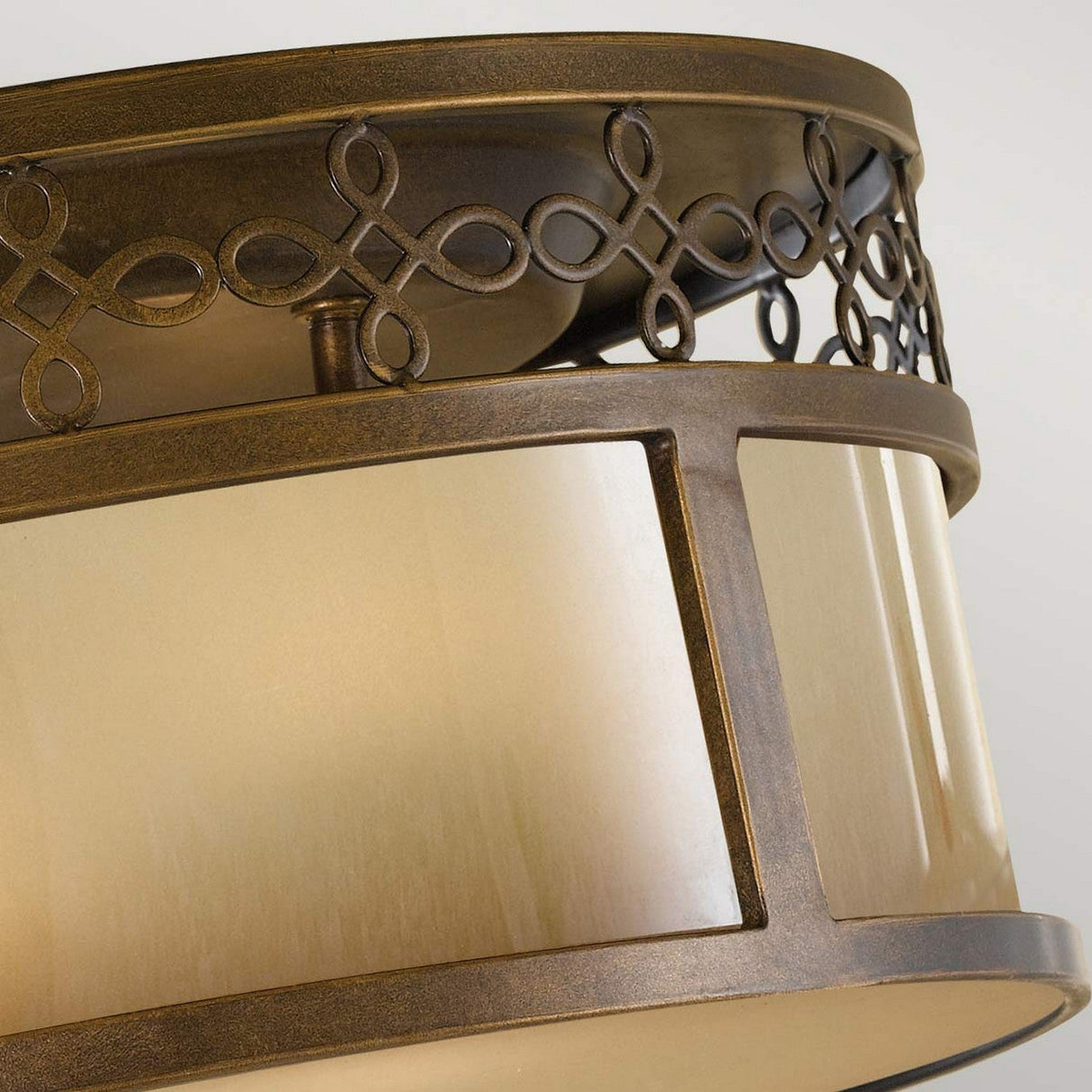 Presenting a detailed look at the Justine 3 Light Flush in Astral Bronze, this decorative ceiling light fixture emanates rustic elegance. It boasts a circular design with handcrafted iron details and ornate looped patterns along the rim, enhanced by a frosted glass panel for a timeless, vintage aesthetic.