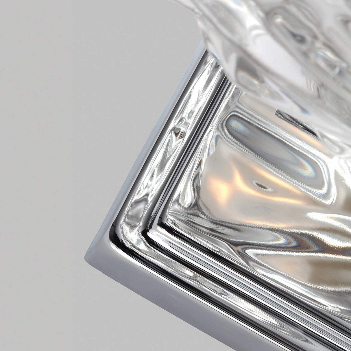 A close-up of a polished chrome square base featuring a crystal object on top, highlighting its gleaming surface and sleek design against a neutral background—perfectly capturing the elegance of the Kalli 1 Light Wall Light - Polished Chrome.