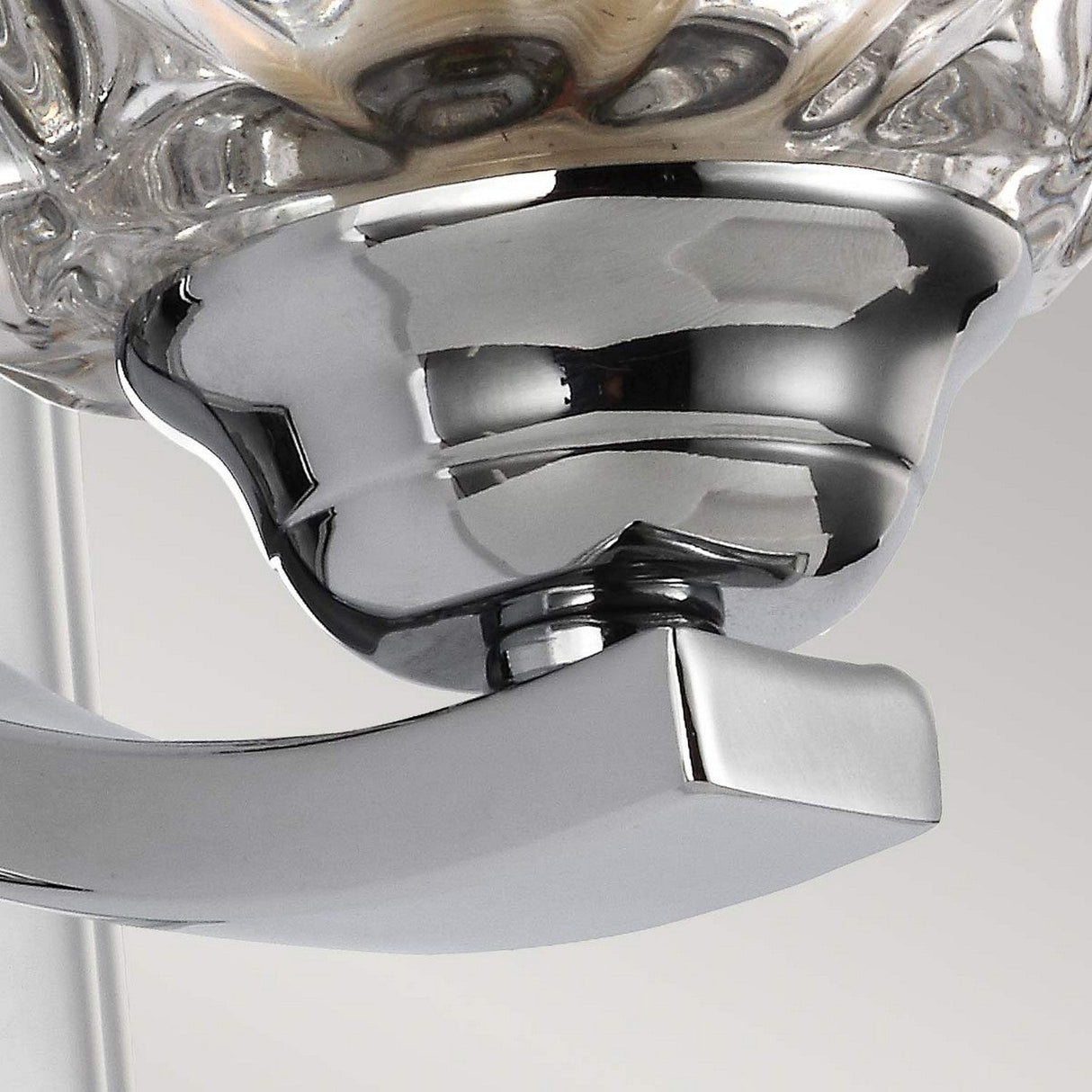 Close-up of a Kalli 1 Light Wall Light - Polished Chrome showcasing its textured crystal glass shade, set against a neutral background. The design highlights smooth surfaces and intricate detailing in polished chrome.