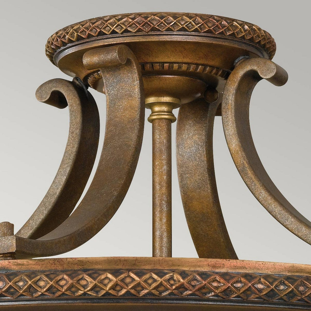 Close-up of the Kelham Hall 2 Light Semi Flush fixture in Firenze Gold/British Bronze, showcasing intricate scrollwork and a decorative base with a diamond pattern. The design exudes a vintage and elegant charm, reminiscent of fixtures found in historic venues like Kelham Hall.