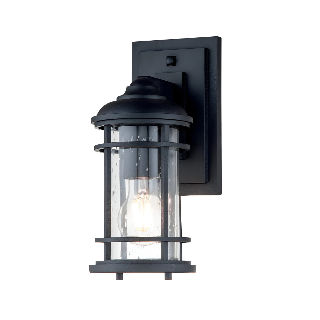 The Lighthouse 1 Light Outdoor Small Wall Lantern in textured black has a rectangular mounting plate and features a cylindrical glass cover encased in a metal grid frame. Its textured glass, paired with the visible light bulb inside, emits a soft glow that adds a touch of nautical-inspired design to your outdoor space.